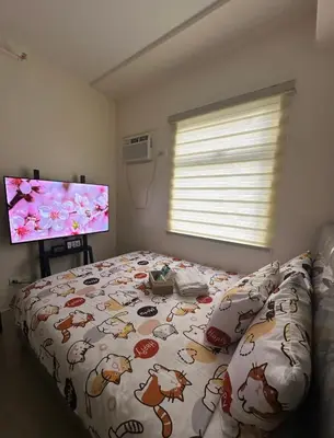 a bedroom with a bed and a flat screen tv at Staycation in Sucat Road in Manila
