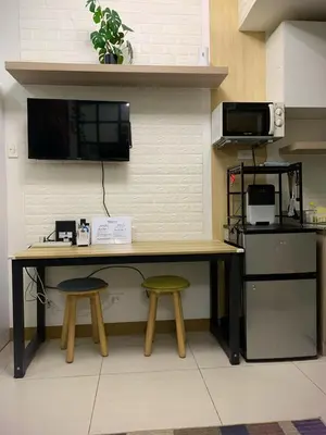 a desk with two stools in a kitchen with a microwave at Comfy Studio near Southmall Las Piñas in Manila