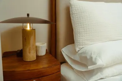 a lamp on a wooden table next to a bed at The Luxe Haven at BGC in Sampong