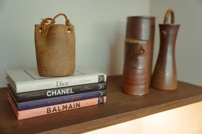 a pile of books sitting on a shelf with vases at The Luxe Haven at BGC in Sampong