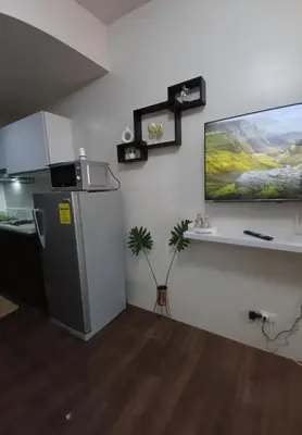 a kitchen with a refrigerator and a tv on the wall at Cozy Pad-50th in Manila