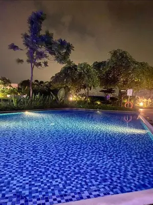 a large blue swimming pool at night at Cozy Pad-50th in Manila