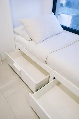 a white bed with white drawers and a pillow at Canopyproperties in Manila