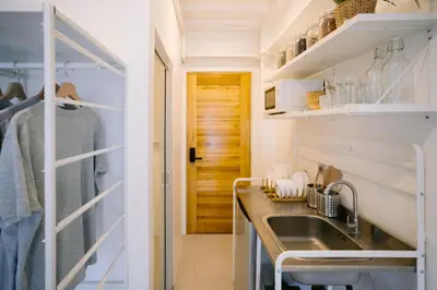 a kitchen with white walls and a sink and a door at Canopyproperties in Manila