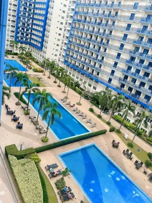 an aerial view of a hotel with two pools and palm trees at Staycation 2 Bedroom at Sea Residences Pasay across Mall of Asia near NAIA Airport in Manila