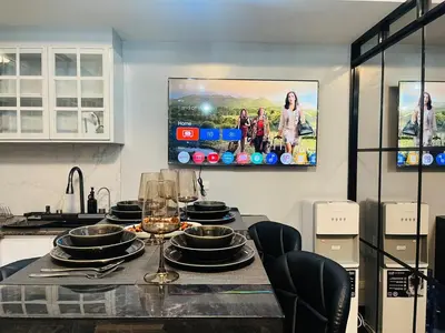 a kitchen with a table with a tv on the wall at Venice Luxury Residences Grand Canal View- Tower E in Manila