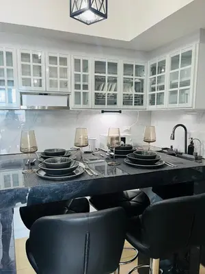 a kitchen with a table with black chairs and white cabinets at Venice Luxury Residences Grand Canal View- Tower E in Manila
