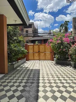 a garage with a wooden gate and flowers at Big Beautiful House in Pasig in Manila
