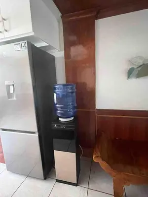 a small black table with a blue bowl on it next to a refrigerator at Big Beautiful House in Pasig in Manila