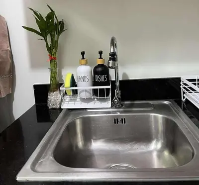 a kitchen sink with two soap bottles and a faucet at Cozy Haven in Manila