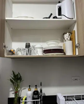 a kitchen shelf with dishes and utensils on it at Cozy Haven in Manila