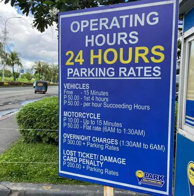 a sign for a hours parking rates at Cozy Haven in Manila