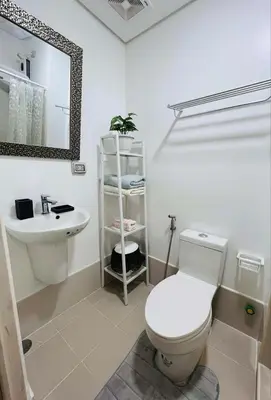 a white bathroom with a toilet and a sink at Sarah's Place at Light Residences in Manila
