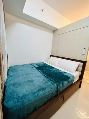 a bedroom with a bed with a blue blanket at Sarah's Place at Light Residences in Manila