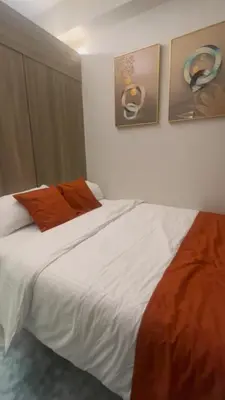 a bedroom with a large white bed with orange pillows at CitySoul in Manila