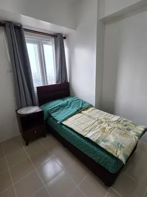 a small bedroom with a bed and a window at 2 BR Penthouse with Sunset View in Manila