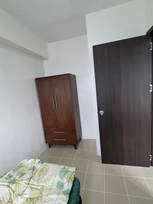 a bedroom with a bed and a wooden cabinet at 2 BR Penthouse with Sunset View in Manila