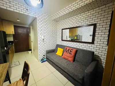a living room with a gray couch with two pillows at Simple Pasay Getaway - Entire Apartment for Rent in Manila