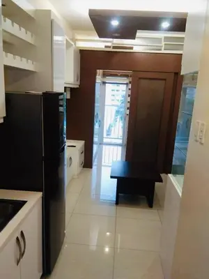 a kitchen with a black refrigerator and a table in it at Charming 1-Bedroom Apartment in the Heart of Pasay City in Manila