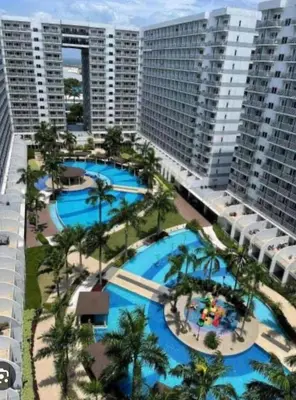 an aerial view of two pools with palm trees and buildings at Ultra Pasay City Apartment for Rent - Perfect for Short-Term Stay Front of MOA in Manila