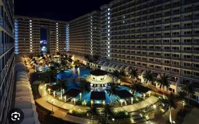 a large building with a large pool in front of it at Timeless Pasay City Apartment for Rent in Manila