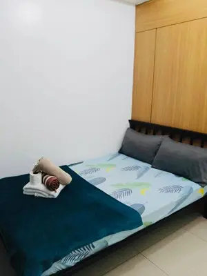 a bedroom with a bed with a green comforter at Gentle Pasay City Apartment for Rent - Perfect Family Getaway Near Mall of Asia in Manila