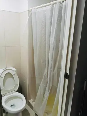 a bathroom with a toilet and a shower curtain at Gentle Pasay City Apartment for Rent - Perfect Family Getaway Near Mall of Asia in Manila