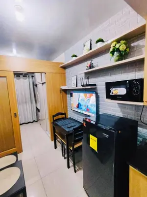 a room with a kitchen with a television and a table at Peaceful Pasay Oasis - Entire Apartment for Rent in Manila