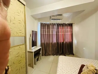 a bedroom with a bed and a window with a television at Dainty Pasay City Apartment for Rent - Entire House Front of Mall of Asia in Manila