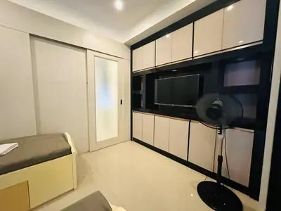a small room with a television and a microwave at Quaint 2BR Connected Apartment in Pasay City - Perfect for Families front of MOA in Manila