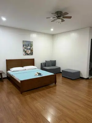 a bedroom with a bed and a couch and a fan at La Belladoza near Airport in Manila