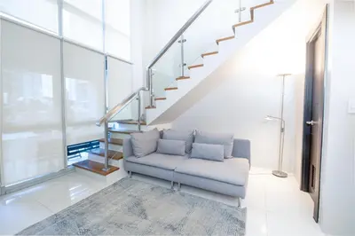 a living room with a couch and stairs at BGC Spacious 1BR Loft Uptown in Manila