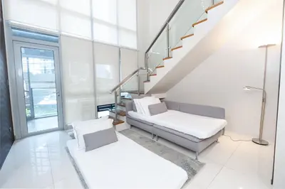 a white room with a staircase and a couch at BGC Spacious 1BR Loft Uptown in Manila