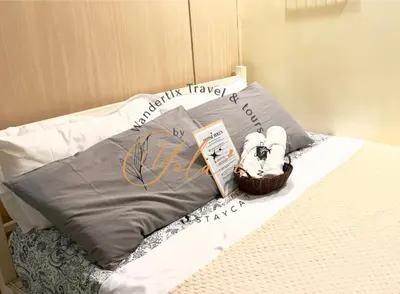 a bed with a blanket and a basket of towels at Yola's Staycation - Jazz Residences Makati City in Manila