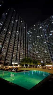 a large building with a green pool in front of it at Yola's Staycation - Jazz Residences Makati City in Manila