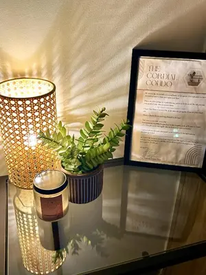 a glass table with a potted plant and a lamp at Cordial Condo in Manila