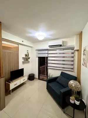 a living room with a blue couch and a television at Cordial Condo in Manila
