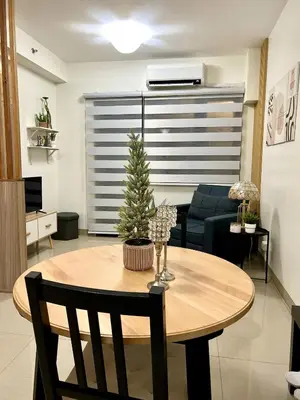 a small christmas tree on a wooden table in a living room at Cordial Condo in Manila