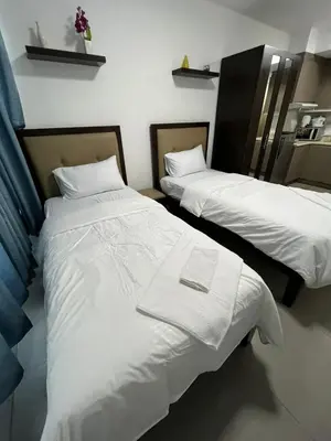 two beds in a room with white sheets at The Serenity Tower 3114 in Manila