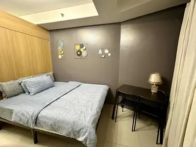 a bedroom with a bed and a table with a lamp at Shell Residence Pasay MOA with 2 Beds by G&K in Manila
