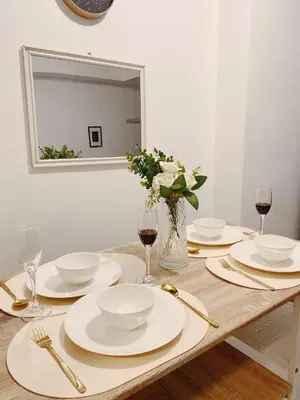 a wooden table with white plates and glasses of wine at Staycation in Marymount in Manila