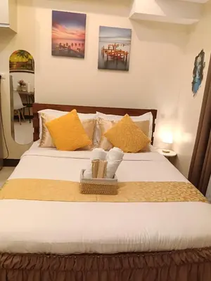 a bedroom with a large bed with yellow pillows at McKinley Hills Taguig Haven in Manila