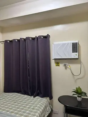 a bedroom with a bed with a curtain and a tv at Seaside Stay in Manila