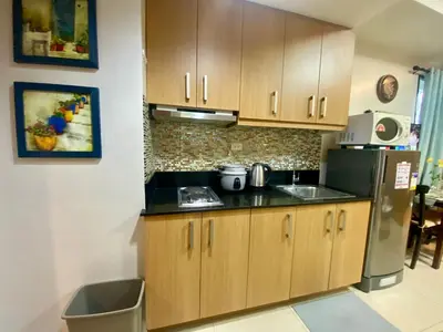 a kitchen with wooden cabinets and a refrigerator at Cousins' Haven Staycation at SHELL RESIDENCES near MOA and NAIA in Manila