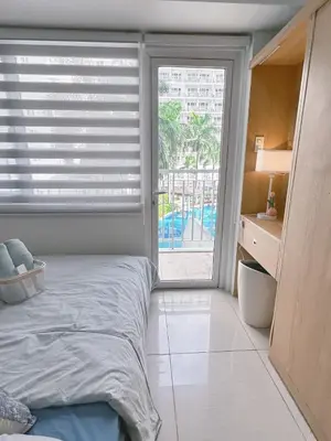 a bedroom with a bed and a large window at Staycapades at Shell Residences in Manila
