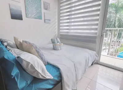 a living room with a couch and a window at Staycapades at Shell Residences in Manila
