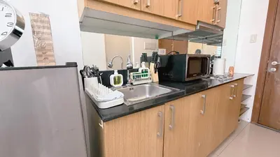 a kitchen with a sink and a microwave at Staycapades at Shell Residences in Manila