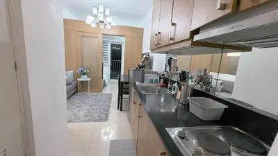 a kitchen with two sinks and a living room at Staycapades at Shell Residences in Manila