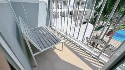 a porch with a bench and chairs on a balcony at Staycapades at Shell Residences in Manila