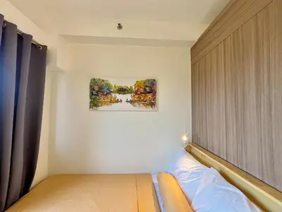 a bedroom with a bed and a painting on the wall at Liwayway Suites in Manila